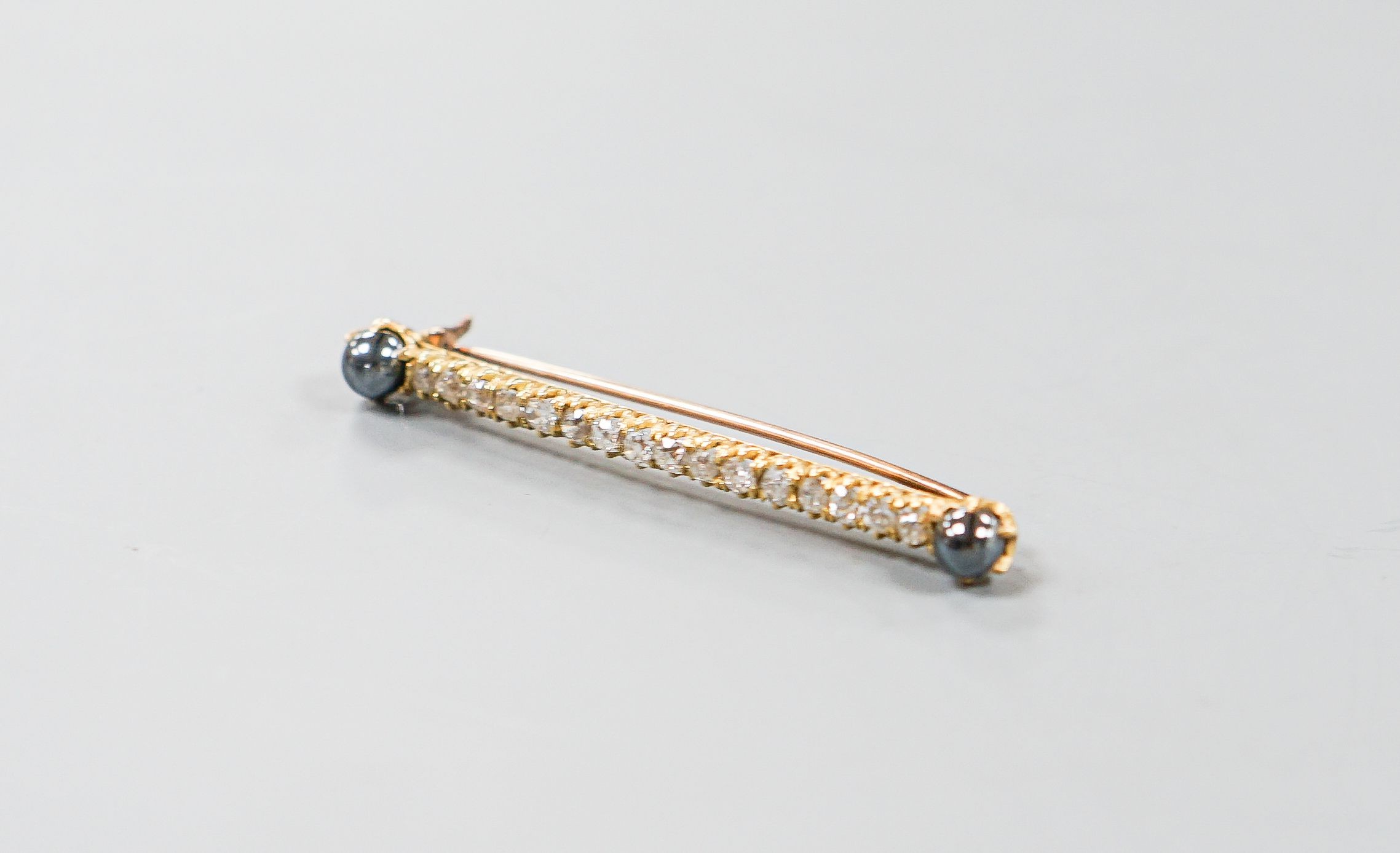 A yellow metal, two stone hematite and sixteen old cut diamond set bar brooch, 52mm, gross weight 5 grams.